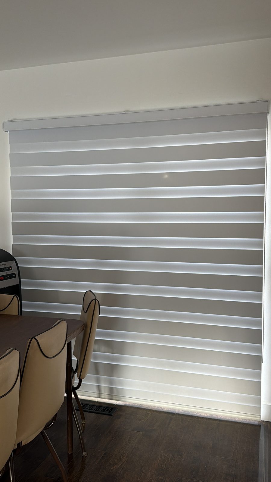 White zebra blinds on a patio door beside a dining table, installed by SMI