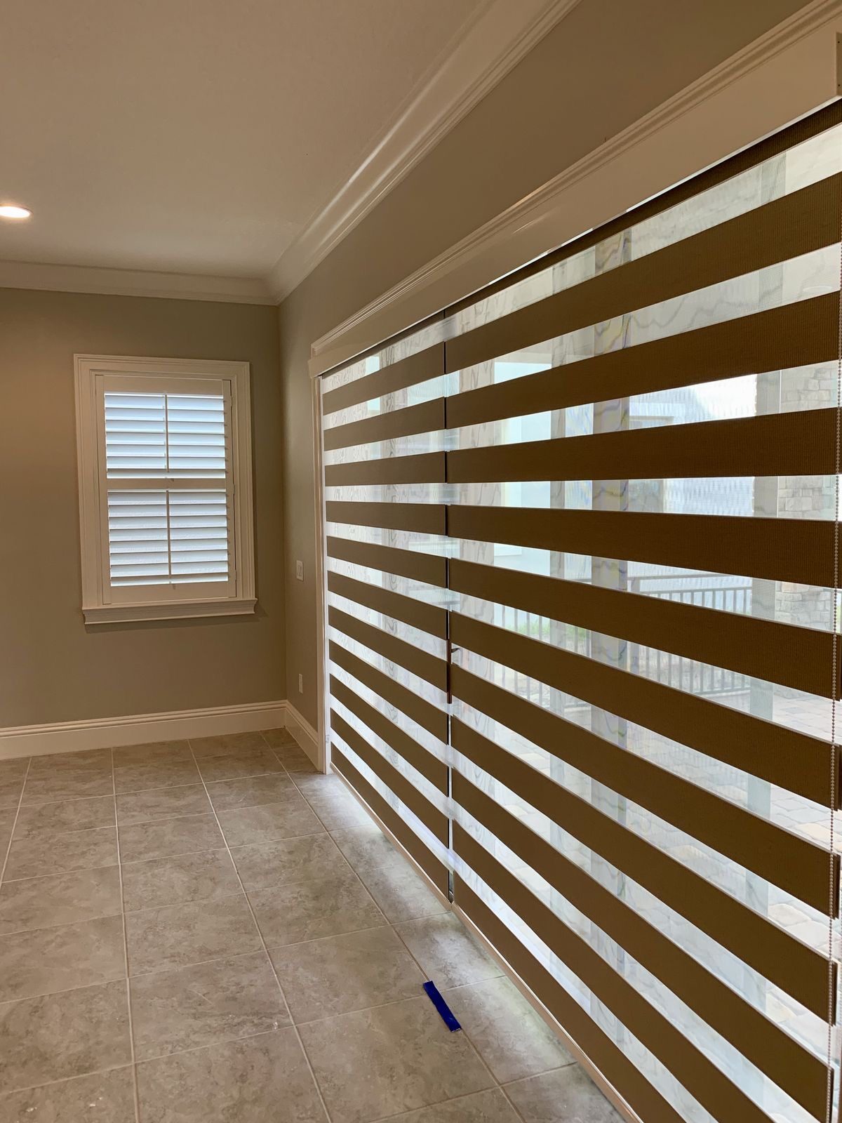Newly installed zebra blinds covering a full wall of sliding glass doors, photographed by SMI right after installation